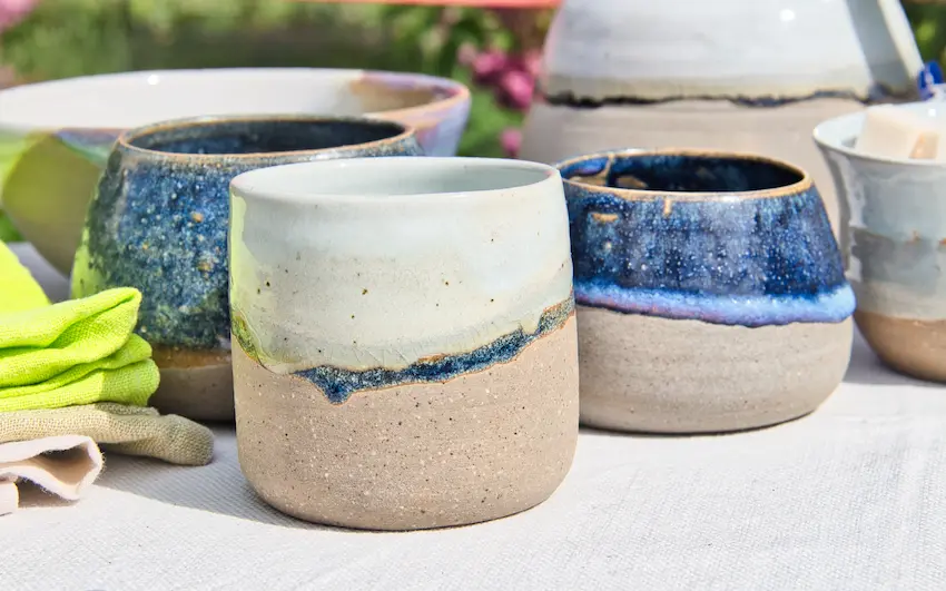 Créations en céramique : tasses, sucrier, assiette en arrière plan